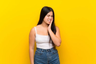 Asyalı genç bir kız diş ağrısı ile izole edilmiş sarı arka plan.