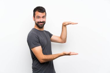 İzole edilmiş beyaz arka plan üzerinde genç yakışıklı bir adam reklam koymak için kopyalama alanı tutuyor