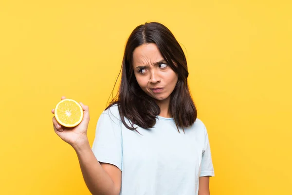 Junge Brünette Frau Hält Eine Orange Mit Traurigem Gesichtsausdruck — Stockfoto