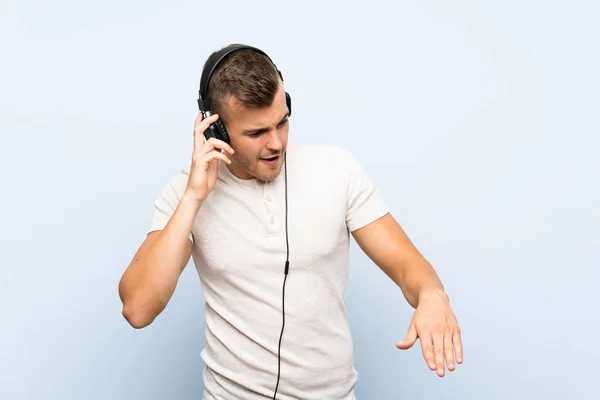 Mladý Pohledný Blonďák Přes Izolované Modré Pozadí Poslouchá Hudbu Sluchátky — Stock fotografie