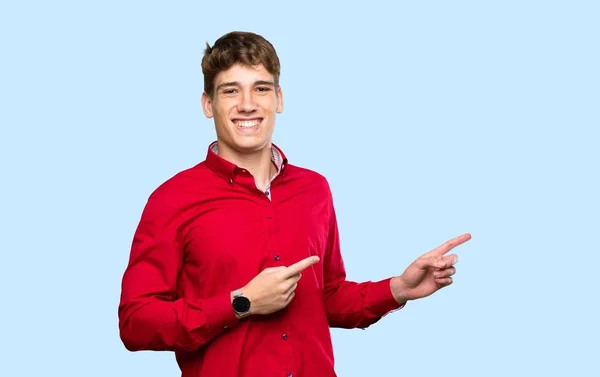 Hezký Mladý Muž Ukazuje Prstem Stranu Přes Izolované Modré Pozadí — Stock fotografie