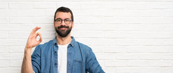 Schöner Mann Mit Bart Über Weißer Ziegelmauer Zeigt Zeichen Mit — Stockfoto