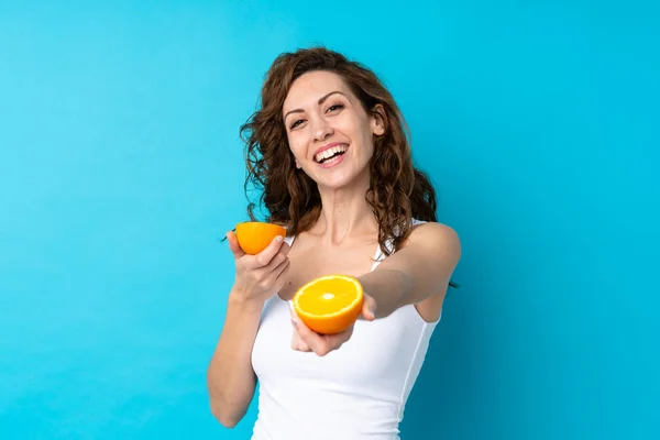 Kıvırcık Saçlı Genç Bir Kadın Portakalı Mavi Arka Planda Tutuyor — Stok fotoğraf
