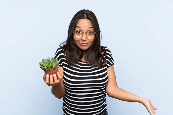 Junge Brünette Frau Hält Eine Pflanze Mit Schockiertem Gesichtsausdruck — Stockfoto