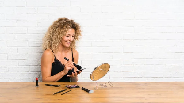 Jeune femme avec beaucoup de brosse de maquillage dans une table — Photo