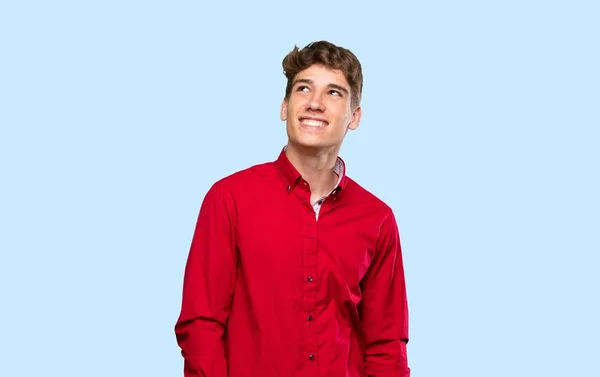 Guapo Joven Riendo Mirando Hacia Arriba Sobre Fondo Azul Aislado — Foto de Stock