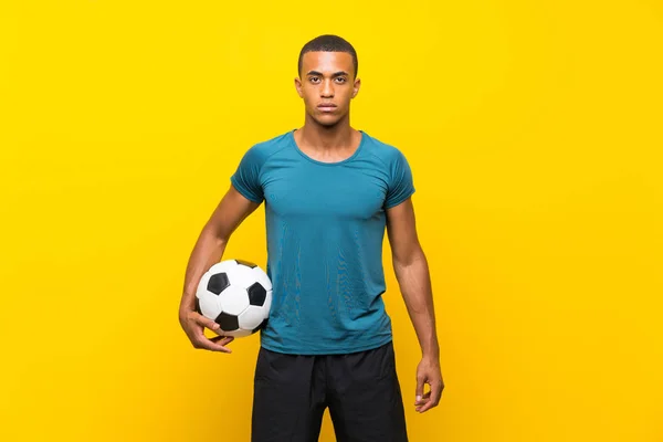 Afro-americano jogador de futebol homem sobre isolado amarelo backgroun — Fotografia de Stock