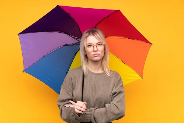 Young Blonde Woman Holding Umbrella Isolated Yellow Wall Keeping Arms — 스톡 사진