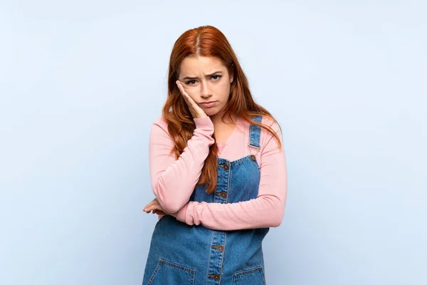 Adolescente Ruiva Menina Com Macacão Sobre Isolado Fundo Azul Infeliz — Fotografia de Stock