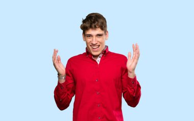 Yakışıklı genç adam soyutlanmış mavi arka planda gülüyor