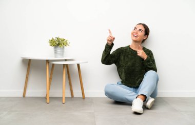 Yerde oturan genç bayan işaret parmağıyla işaret etmek harika bir fikir.