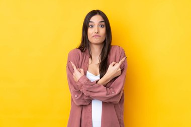 İzole edilmiş sarı arka planda genç esmer bir kadın. Yan taraftakilerin şüpheleri olduğunu gösteriyor.