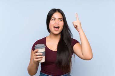 Genç Asyalı kız elinde kahve ile çözümü bulmak için parmağını kaldırıyor.
