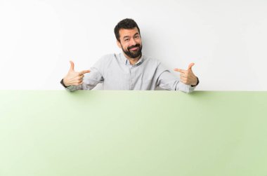 Sakallı yakışıklı genç adam elinde kocaman boş bir levha, gururlu ve kendini beğenmiş.
