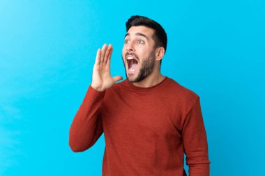 Sakallı, mavi arka planda genç yakışıklı bir adam ağzı açık bağırıyor.