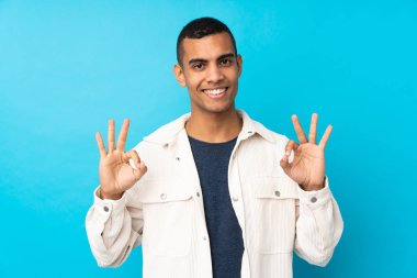 Genç Afro-Amerikalı adam izole edilmiş mavi arka planda parmaklarıyla 