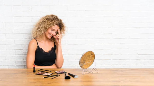 Mujer Joven Con Mucho Maquillaje Cepillo Una Mesa Riendo — Foto de Stock