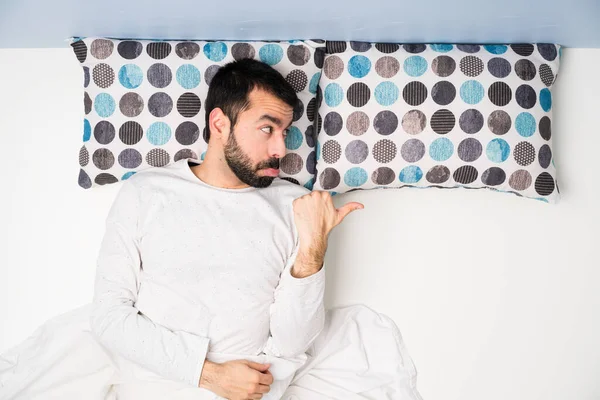 Man in bed in top view unhappy and pointing to the side