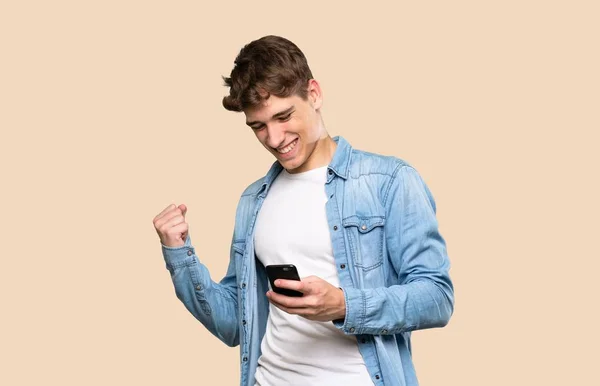 Beau Jeune Homme Avec Téléphone Position Victoire Sur Fond Isolé — Photo