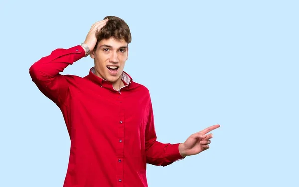 Yakışıklı Genç Adam Şaşırdı Mavi Arka Plan Üzerinde Parmak Işareti — Stok fotoğraf