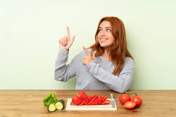 Adolescente Pelirroja Chica Con Verduras Una Mesa Señalando Con Dedo —  Fotos de Stock