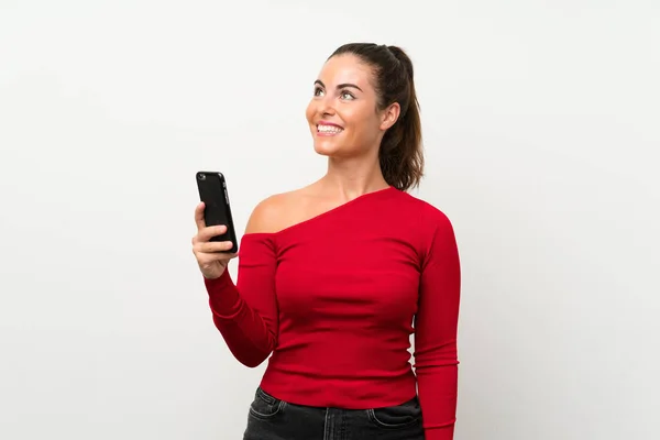 Молода Жінка Використовуючи Мобільний Телефон Дивлячись Вгору Посміхаючись — стокове фото