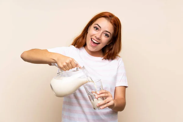 Tinédzser vöröshajú lány kezében egy pohár tejet az elszigetelt háttér — Stock Fotó