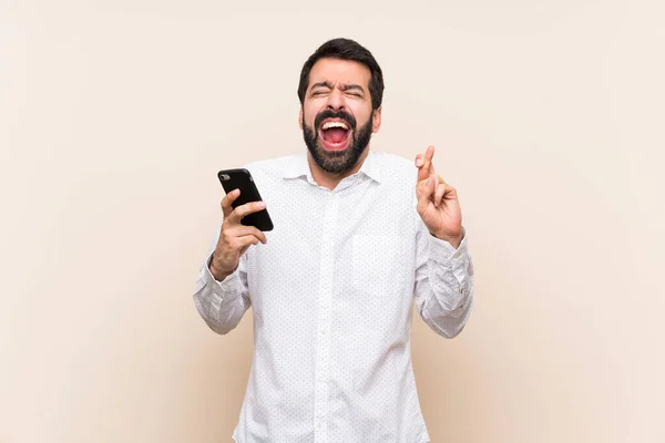 Joven Con Barba Sosteniendo Móvil Con Los Dedos Cruzados —  Fotos de Stock