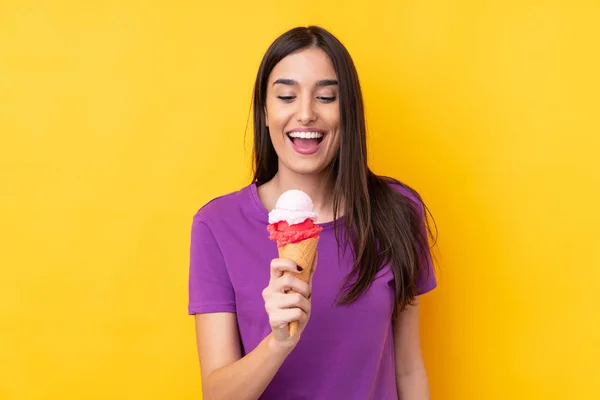 Mladá brunetka žena s kornetovou zmrzlinou přes izolované yello — Stock fotografie