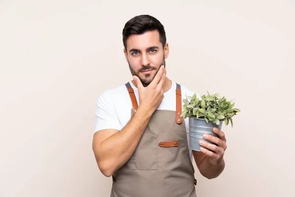 Jardineiro Homem Segurando Uma Planta Sobre Fundo Isolado Pensando Uma — Fotografia de Stock