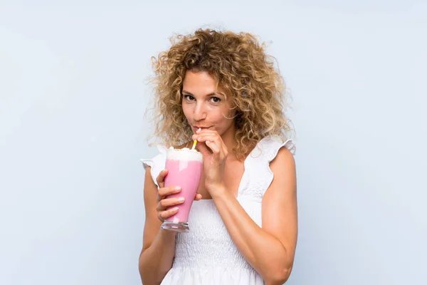 Jeune femme blonde aux cheveux bouclés tenant un milkshake à la fraise — Photo