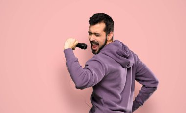 Tişörtlü yakışıklı adam mikrofonla şarkı söylüyor.