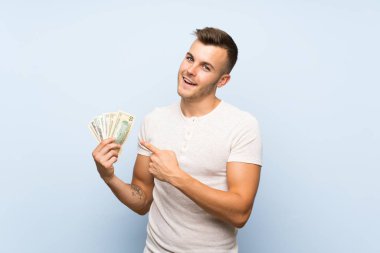 Izole mavi arka plan üzerinde genç yakışıklı sarışın adam çok para alarak