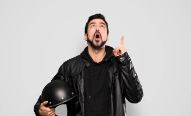 Biker man pointing up and surprised over isolated grey background