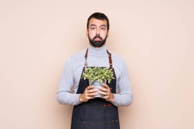 Üzücü ve depresif bir ifadeyle bir bitkiyi izole edilmiş arka planda tutan adam