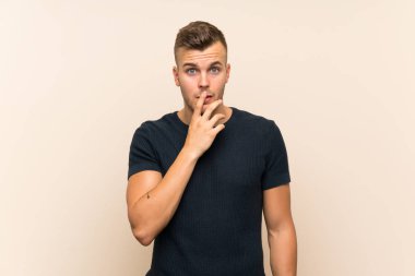 Genç ve yakışıklı sarışın adam, izole edilmiş arka planda şaşırmış ve şaşırmış görünüyor.