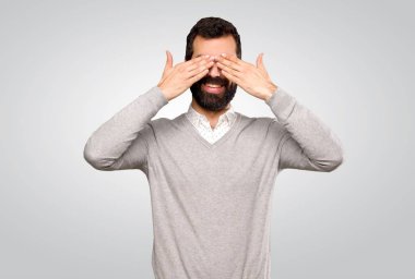 Handsome man covering eyes by hands over isolated grey background