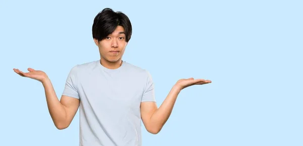 Asian Man Blue Shirt Having Doubts While Raising Hands Isolated — 스톡 사진