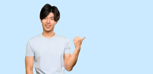 Asijské Muž Modrým Tričkem Ukazuje Stranu Prezentovat Produkt Přes Izolované — Stock fotografie