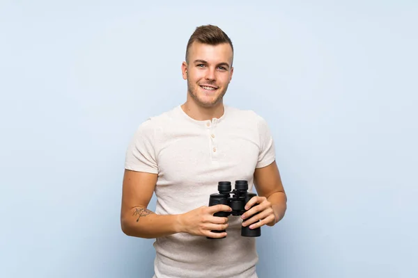 Jovem Homem Loiro Bonito Sobre Fundo Azul Isolado Com Binóculos — Fotografia de Stock