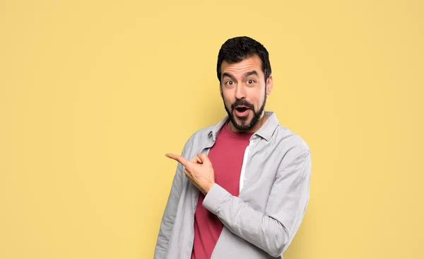 Bel Homme Avec Barbe Surpris Pointant Côté Sur Fond Jaune — Photo