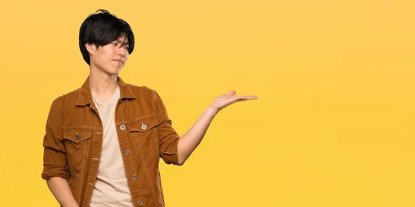 Asian Man Brown Jacket Holding Copyspace Doubts Isolated Yellow Background — 스톡 사진