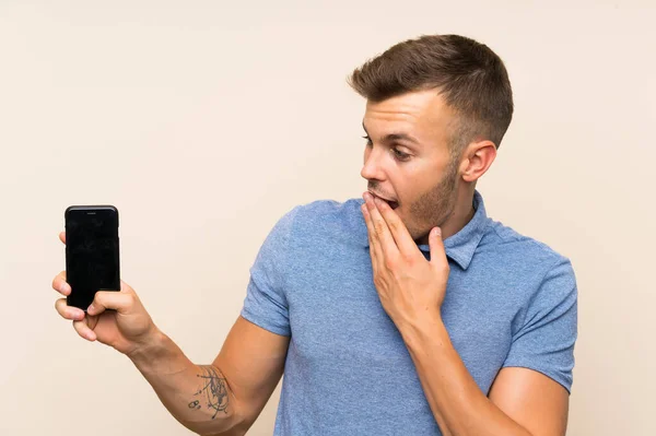 Joven Hombre Rubio Usando Teléfono Móvil Con Sorpresa Expresión Facial —  Fotos de Stock