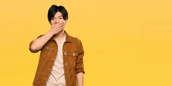 Asian Man Brown Jacket Covering Mouth Hands Isolated Yellow Background — Stock Photo, Image