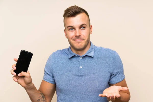 Młody Blondynka Człowiek Pomocą Telefon Komórkowy Wątpliwości Gest Podczas Podnoszenia — Zdjęcie stockowe