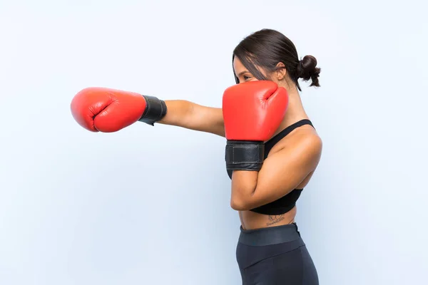 Jovem menina esporte com luvas de boxe sobre fundo azul isolado — Fotografia de Stock