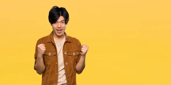 Asian Man Brown Jacket Celebrating Victory Winner Position Isolated Yellow — Stock Photo, Image