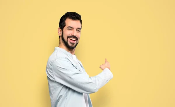 Bonito Homem Com Barba Apontando Para Trás Sobre Fundo Amarelo — Fotografia de Stock