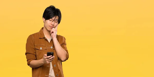 Asian Man Brown Jacket Thinking Sending Message Isolated Yellow Background — 스톡 사진