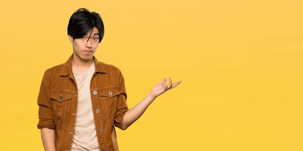 Asian Man Brown Jacket Making Doubts Gesture Isolated Yellow Background — 스톡 사진